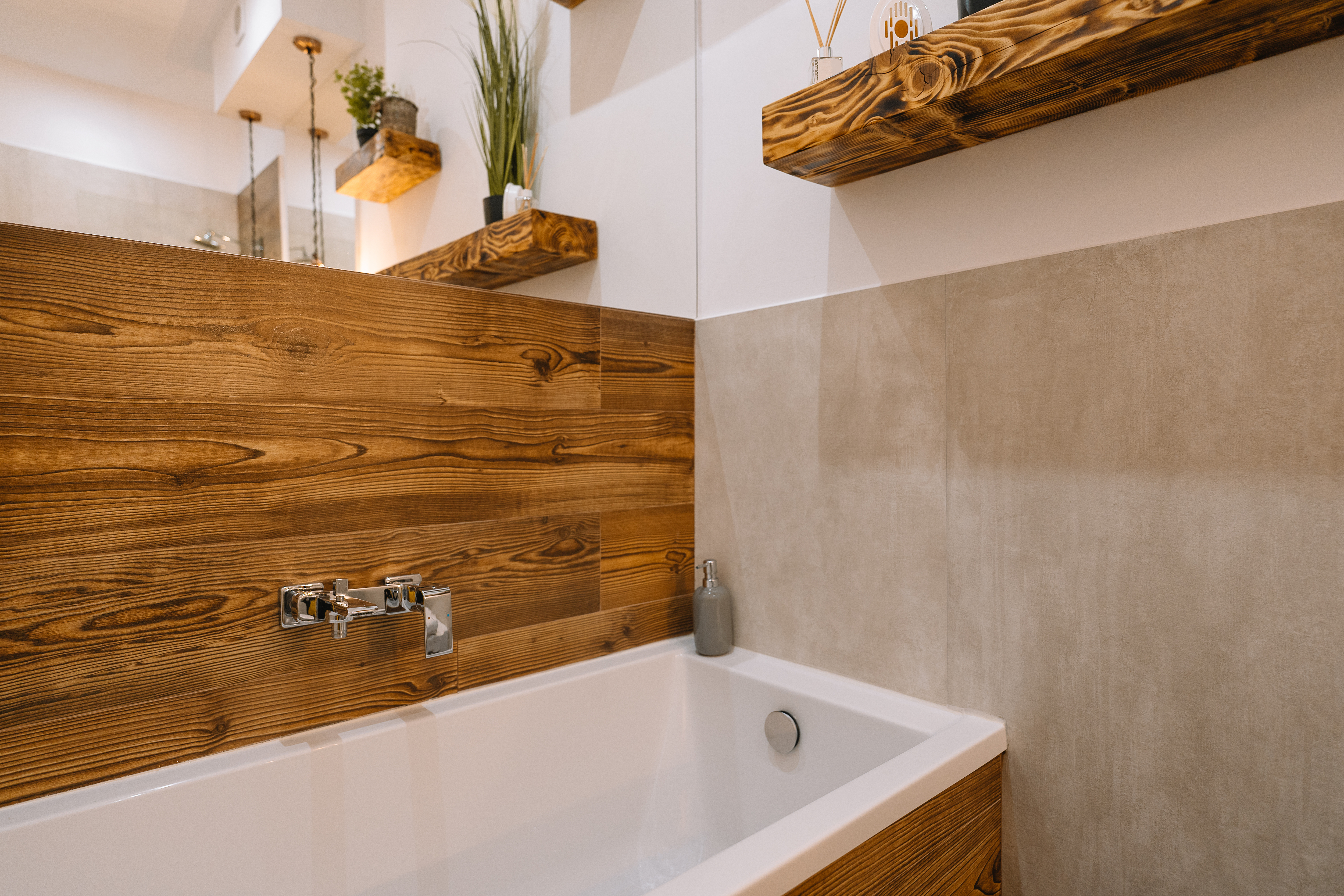 Porcelain and wood bathtub below wooden shiplap accent wall